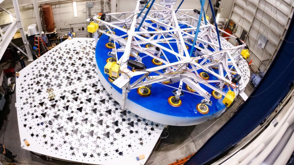 Overhead view of a completed 8.4-meter-diameter primary mirror transport and placement for the Giant Magellan Telescope, suspended above the support system prototype at the University of Arizona’s Richard F. Caris Mirror Lab.