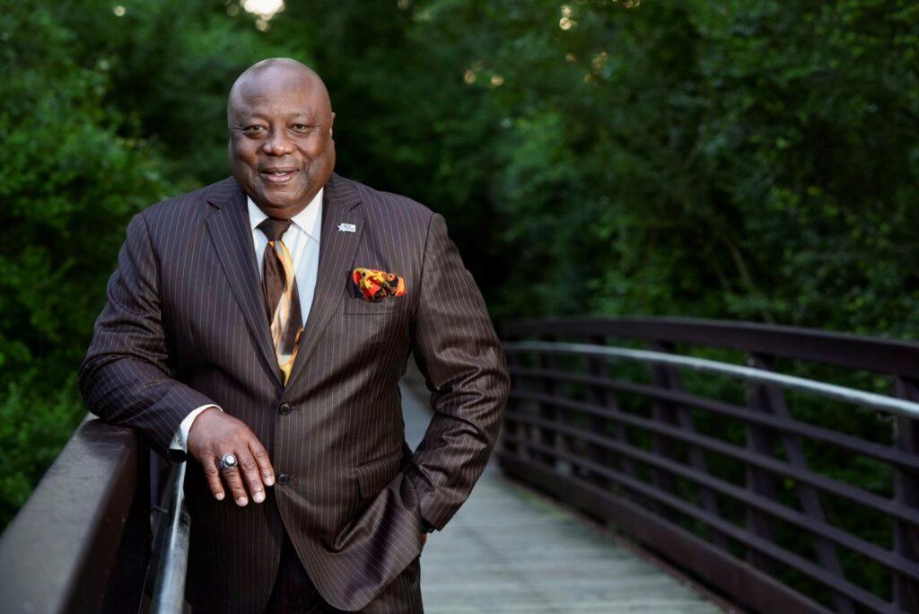 A photo of a man in a suit standing on a bridge.