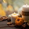 A picture of candles on a wooden table along with small pumpkins and autumn table decor.