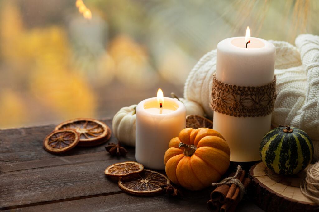 A picture of candles on a wooden table along with small pumpkins and autumn table decor.