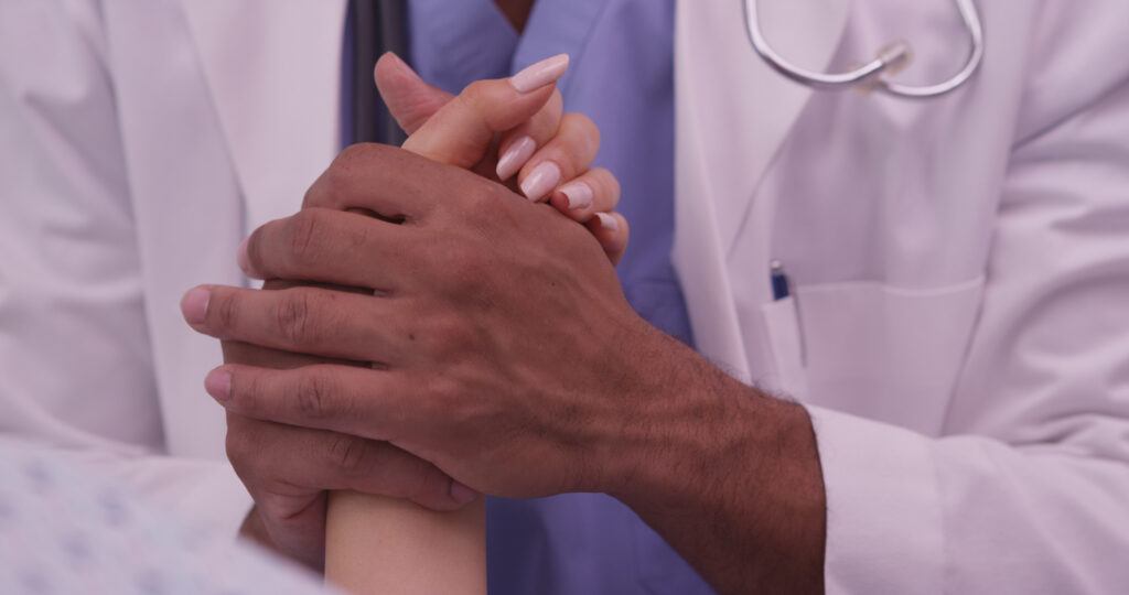 a doctor holds a patient's hand