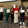 A photo of seven people with awards.