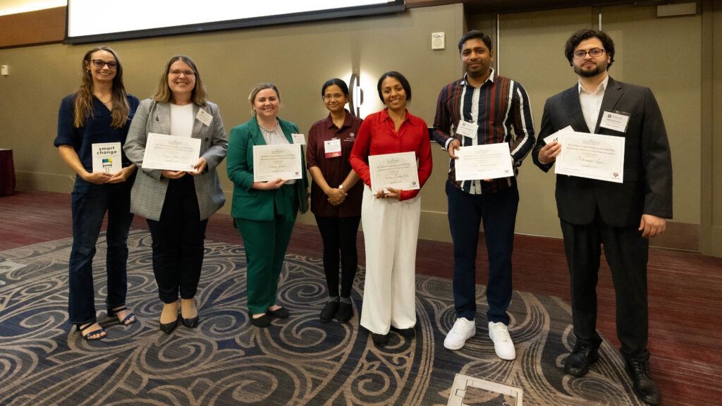 A photo of seven people with awards.