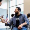 A woman greets a man in an Army veteran in a wheelchair.