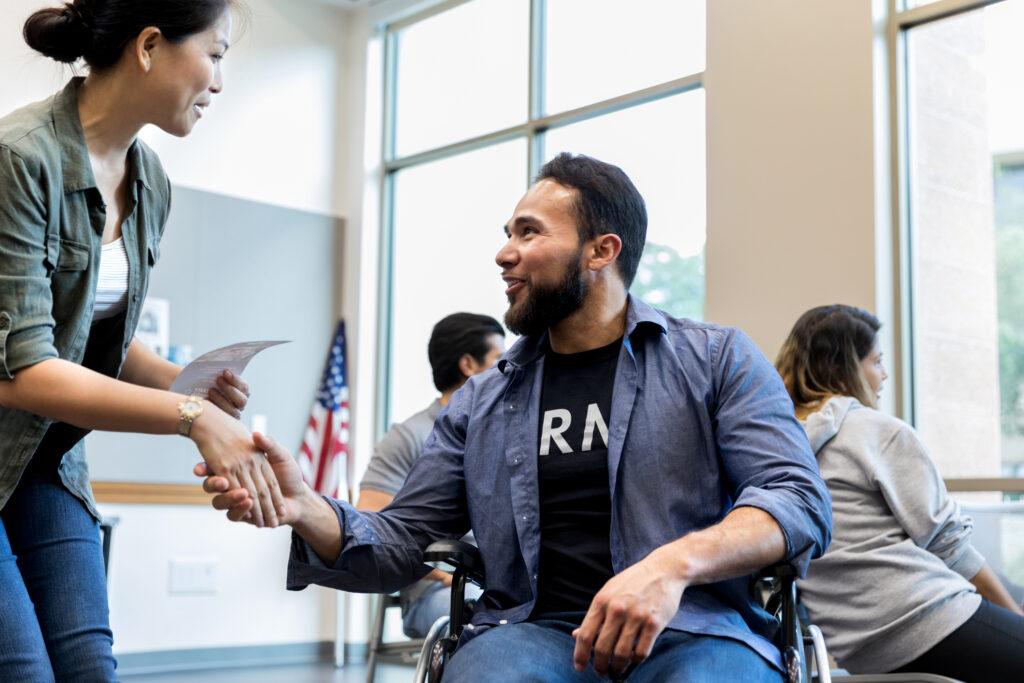 A woman greets a man in an Army veteran in a wheelchair.