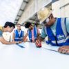 a photo of students dressed in safety gear making measurements with tape measures