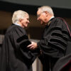 A photo of Texas A&M University President Gen. (Ret.) Mark A. Welsh III shaking hands with former U.S. Ambassador Ryan Crocker during a commencement ceremony at Texas A&M University.