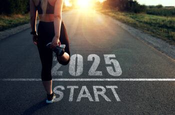 A runner stretching on a road with the words 2025 Start at his feet and a sunrise in the distance.