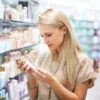 A young woman reads the information on a bottle of lotion.