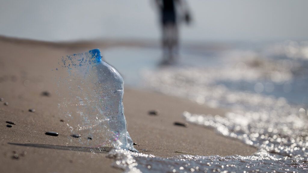 a rendering of a plastic bottle breaking apart on the beach