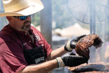 A photo of a man looking at meat after taking it out of the grill.