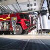 A photo of a firefighter carrying equipment to a fire engine in an airport fire stations.