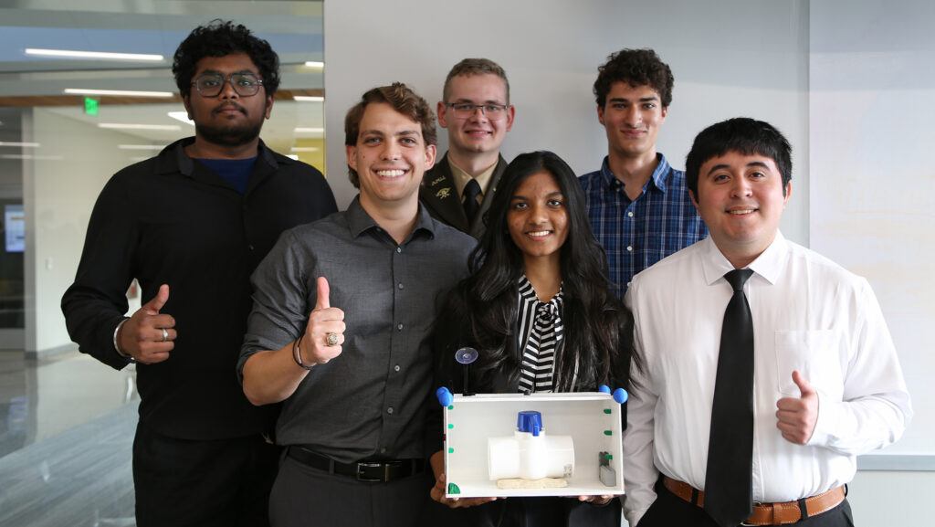 A photo of a group of students standing with a safety device they designed for a Small Modular Reactor.