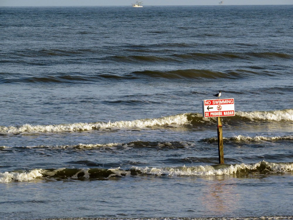 a rip current warning sign on a beach