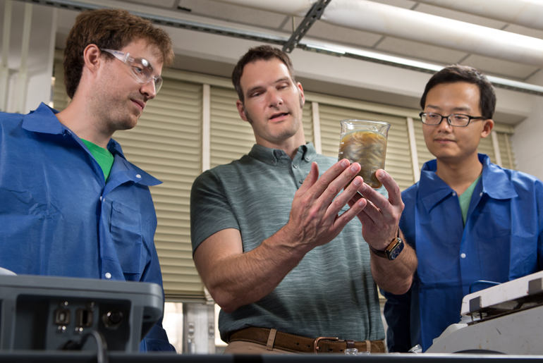 Grunlan (center) discusses the behavior of a clay solution to Ph.D. students Ryan Smith (left) and Yixuan Song. These clay solutions are used in producing clay-based nanocomposite thin films and coatings for the Sandia project. (Photo courtesy Texas A&M College of Engineering)
