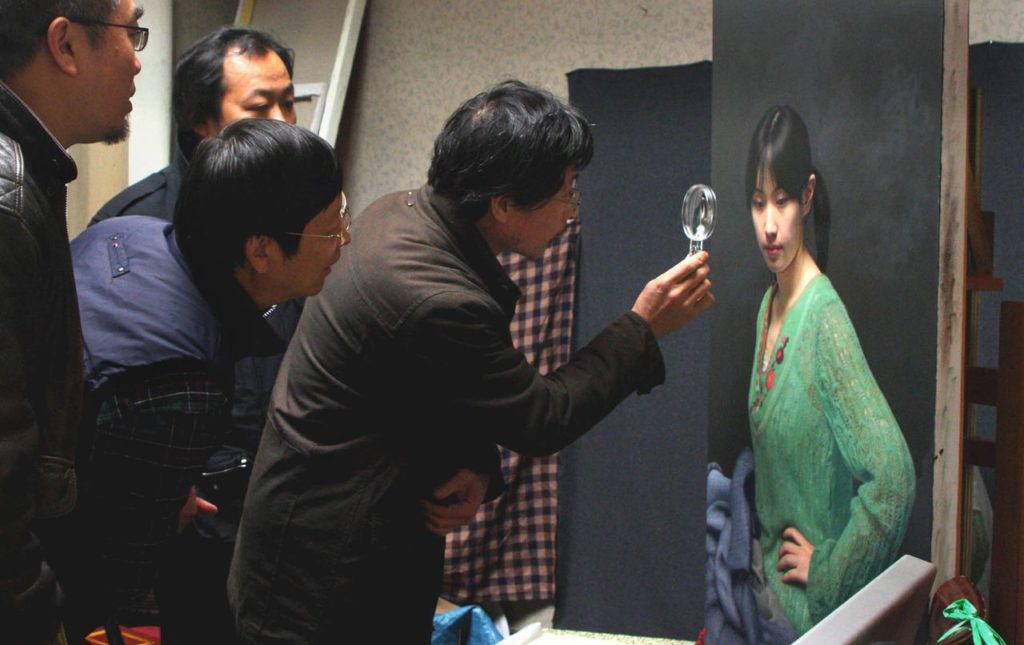 Hyperrealist artist Leng Jun, who paints portraits with photograph-like detail, examines one of his portraits.