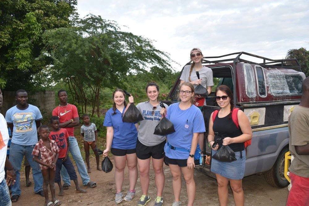 Texas A&M sophomore biology major Avery Young '19 (standing in back of vehicle), distributes bags of food in Haiti.