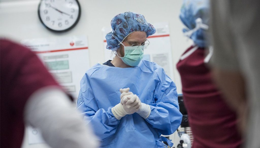 Surgeon in full scrubs examining something