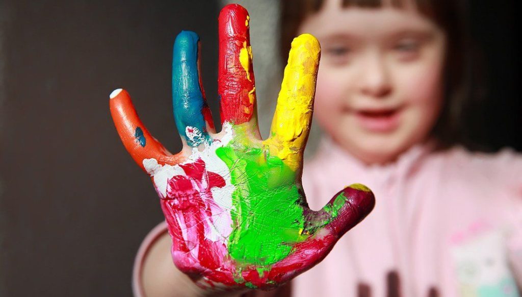 special needs child with painted hands