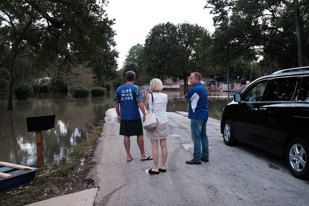 HOUSTON, TX - SEPTEMBER 04: People stand in a flooded neighborhood as Texas moved toward recovery from the devastation of Hurricane Harvey on September 4, 2017 in Houston, Texas. Almost a week after Hurricane Harvey ravaged the city, some neighborhoods still remained flooded and without electricity.