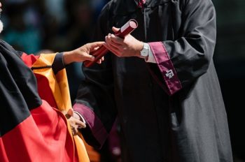 A student is handed a degree at a graduation ceremony.
