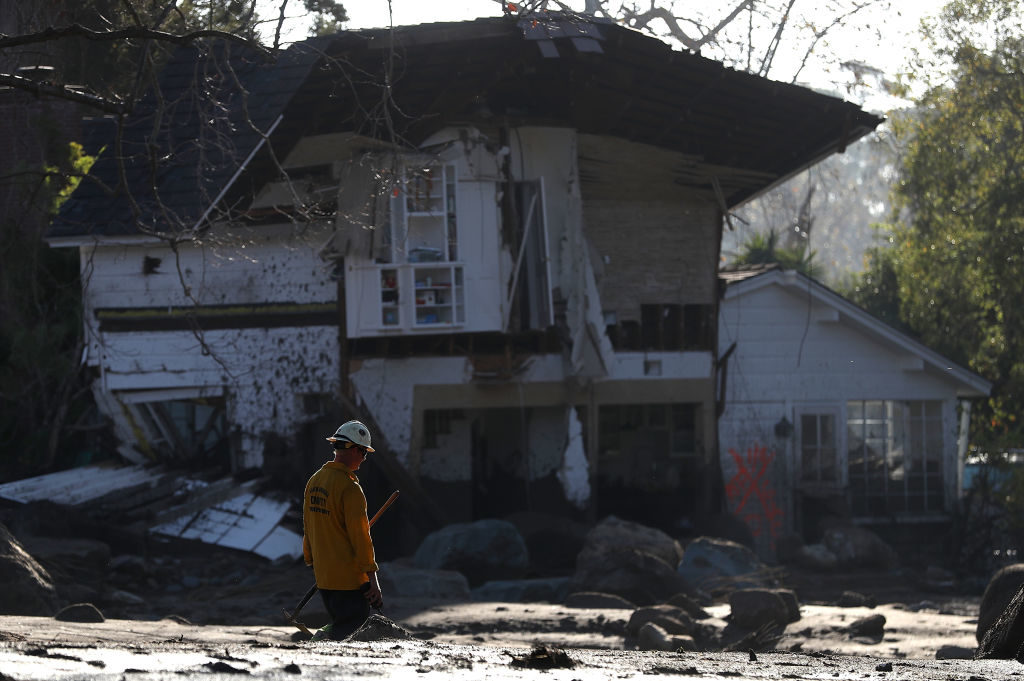 MONTECITO, CA - JANUARY 11: An urban search and rescue team member walks by a home that was destroyed by a mudslide on January 11, 2018 in Montecito, California. 17 people have died and hundreds hundreds of homes have been destroyed or damaged after massive mudslides crashed through Montecito, California early Tuesday morning. (Photo by Justin Sullivan/Getty Images)