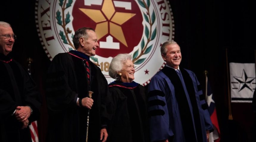 a photo of George H.W. Bush, Barbara Bush and George W. Bush standing in front of an A&M seal in graduation robes