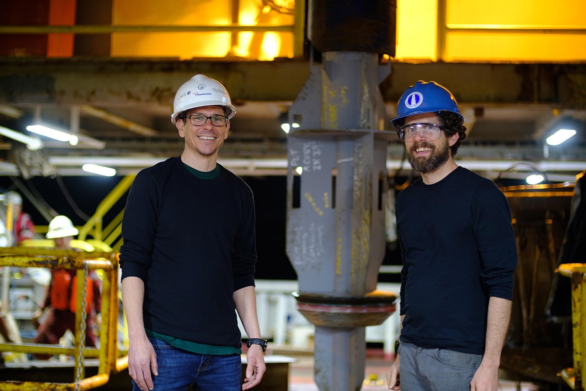 Dr. Patrick Fulton (Right, Texas A&M Geology and Geophysics) and Dr. Demian Saffer (Left, Penn State University) stand in front of one of two sub-seafloor observatories before it is installed beneath the sea, while on board the JOIDES Resolution for IODP Expedition 375. (Patrick Fulton/IODP)