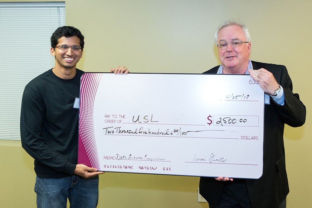 The only member of TEAM USL, doctoral student Sai Vemprala (left) of the College of Engineering, accepts a $2,500 check from Interim Director Simon Sheather of the Texas A&M Institute of Data Science (TAMIDS) for placing first in the graduate student category of the TAMIDS data science competition. (Butch Ireland)