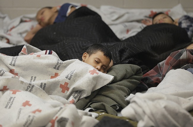 Detainees sleep in a holding cell at a U.S. Customs and Border Protection processing facility, on June 18, 2014, in Brownsville,Texas. Brownsville and Nogales, Ariz. have been central to processing the more than 47,000 unaccompanied children who have entered the country illegally since Oct. 1. (Photo by Eric Gay-Pool/Getty Images)