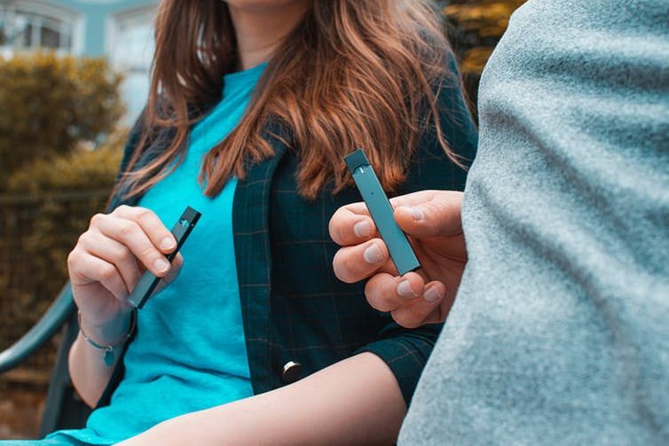 A man and a woman holding a Juul device. (Vaping360.com)
