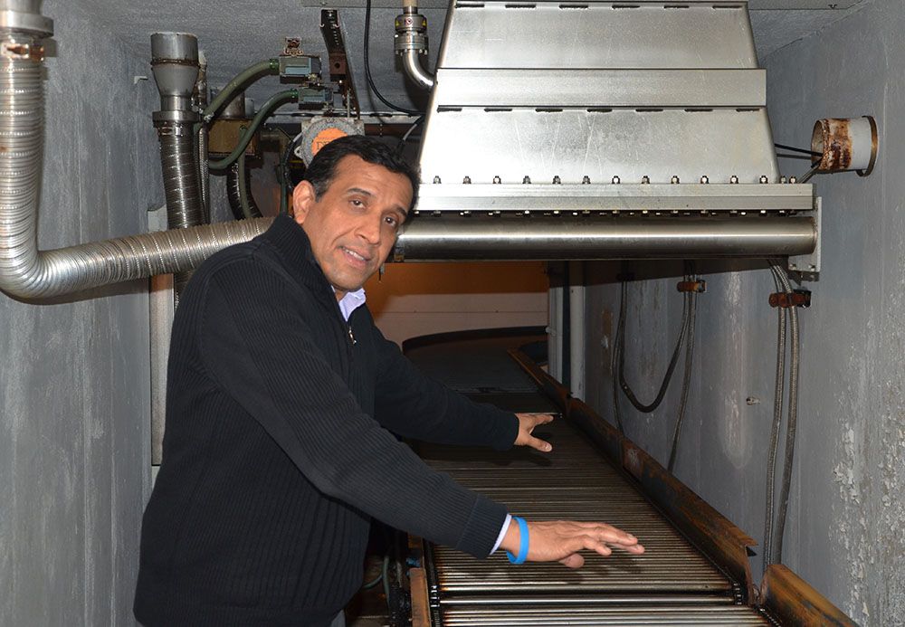 Dr. Suresh D. Pillai shows where food and other materials pass along an automated conveyor belt to be sanitized. Pillai is a Texas A&M AgriLife Research scientist and director of the National Center for Electron Beam Research, College Station. (Texas A&M AgriLife Communications)